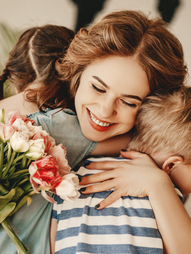 Little children congratulating and hug mother in kitchen